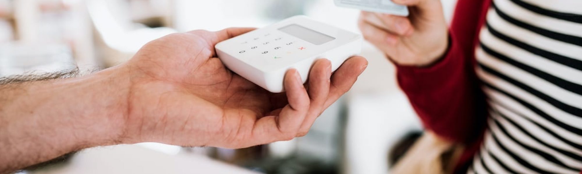 Customer and shop assistant making contactless payment using credit card in a shop. A midsection of customer and shop assistant making wireless or contactless payment using credit card in a shop.